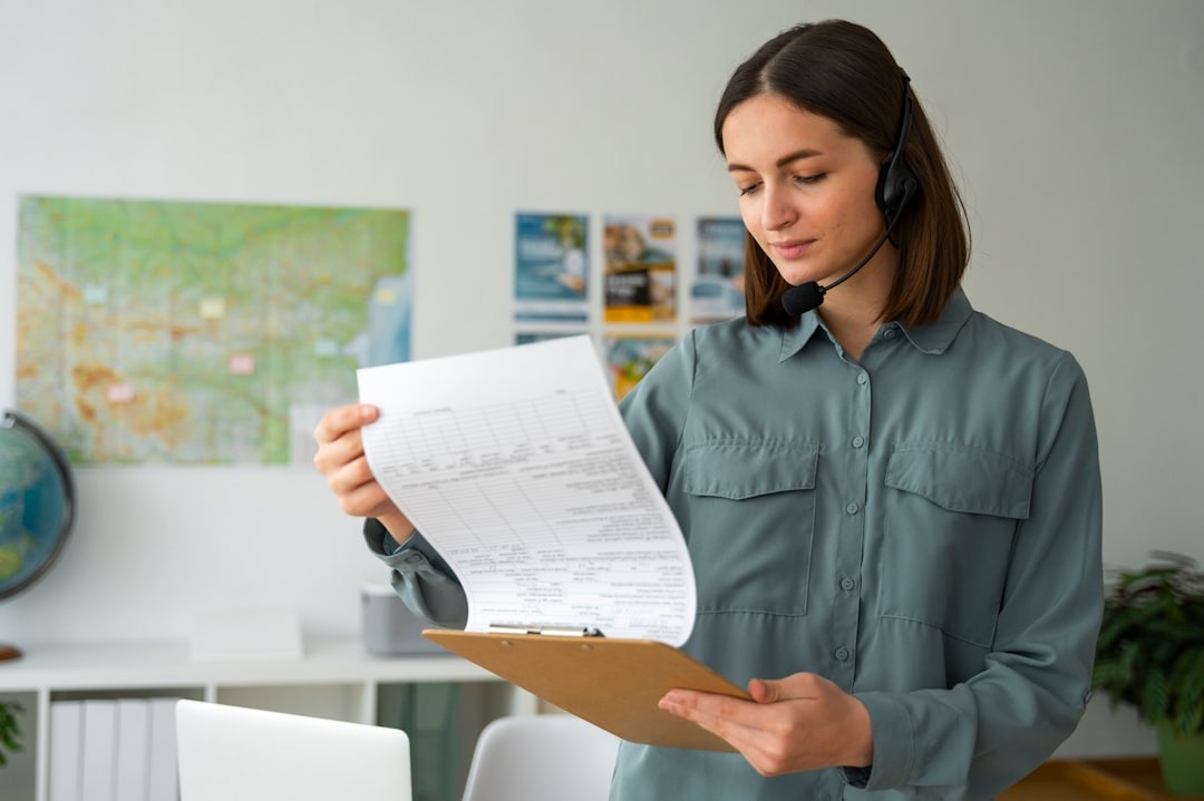 Woman in headset reads from clipboard in an office.